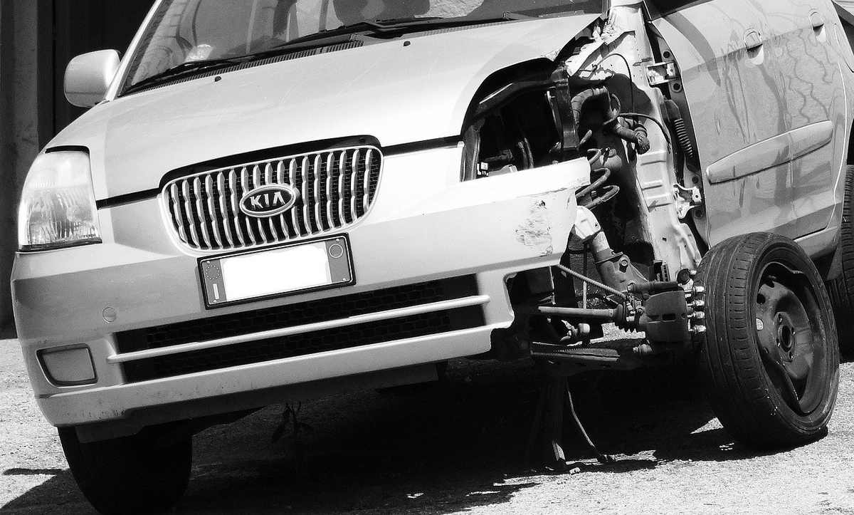 Voiture Kia blanche après choc frontal, moteur visible, roue avant droite absente